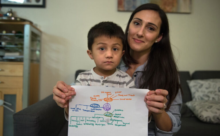 A young boy with special health care needs and his mother hold up his care map.