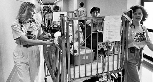Hospital workers wheeling a hospital bed down a hallway