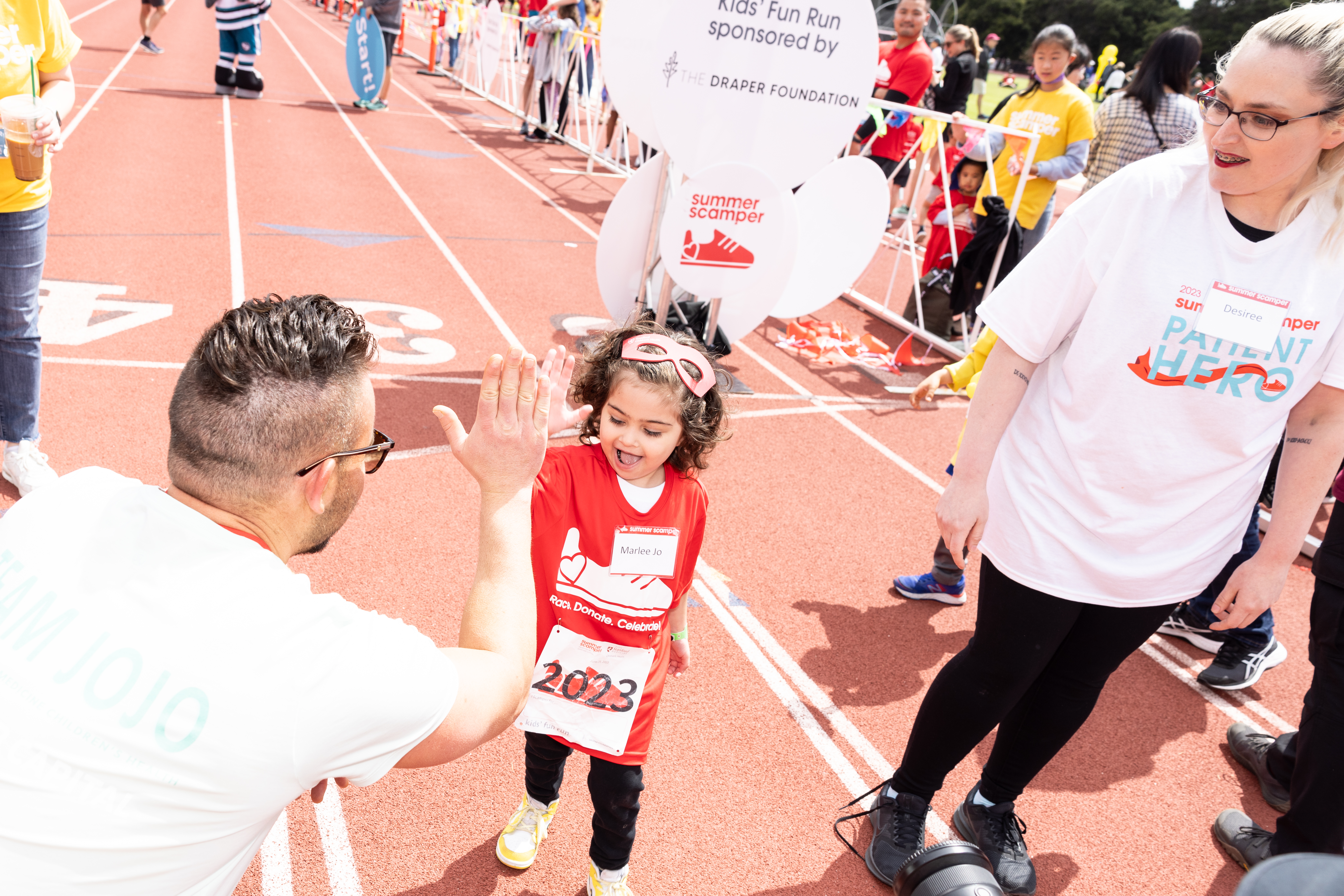 Young girl giving a high-five to a man at the end of the kids' fun run.