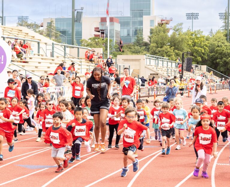 Stanford women's basketball player runs with kids in the kids' fun run at Summer Scamper.