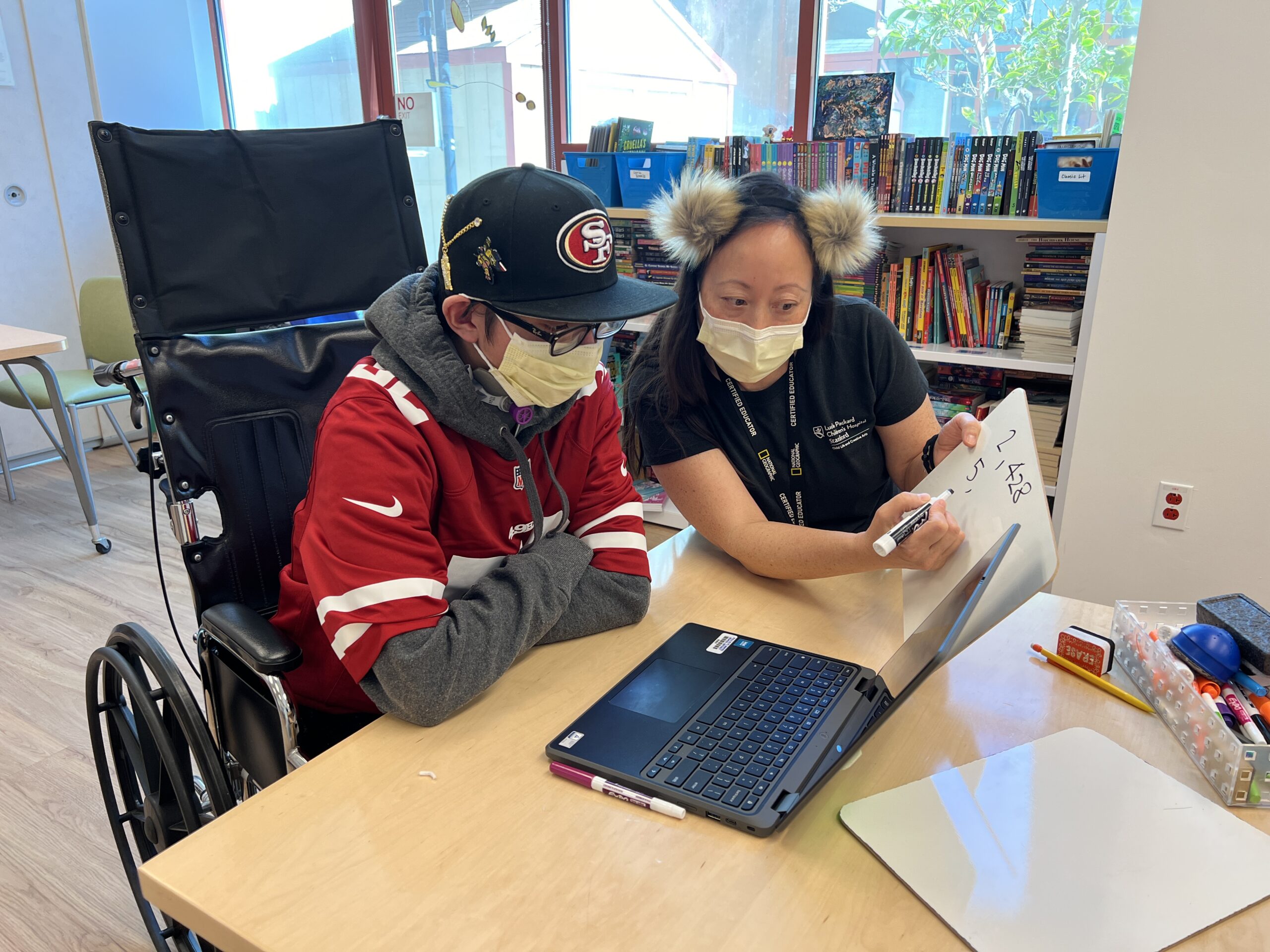 Ruben is seated with his teacher, Kathy Ho.