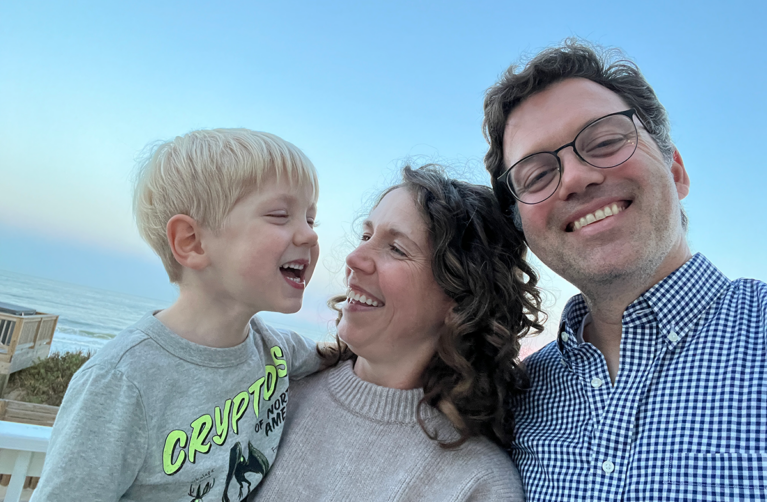 A family of three posing together and smiling.