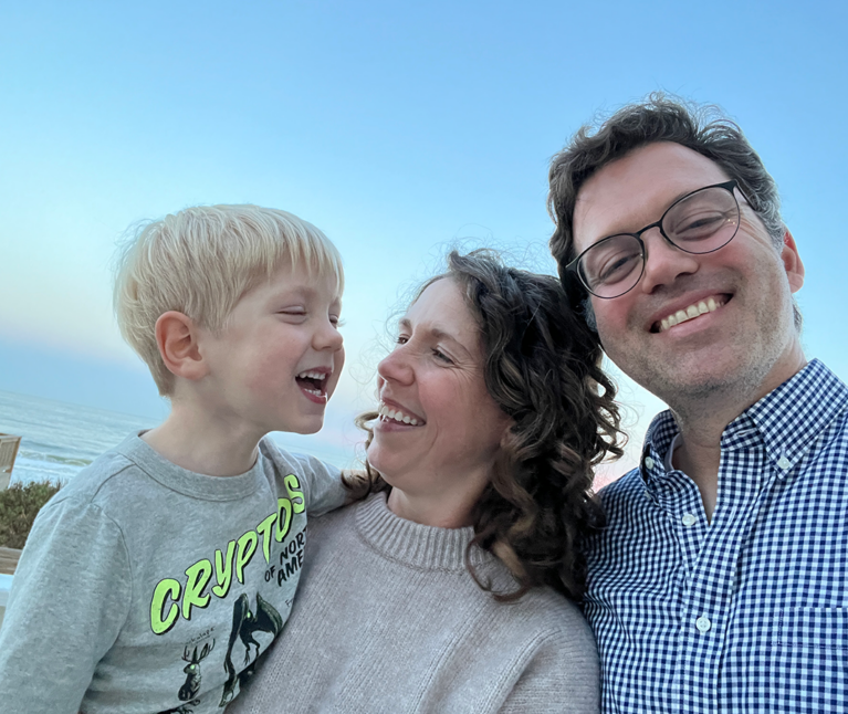 A family of three posing together and smiling.