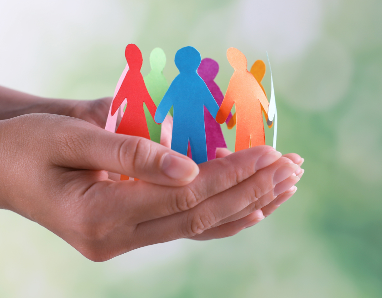 Stock photo of hands holding multicolored paper dolls that are connected and in a circle