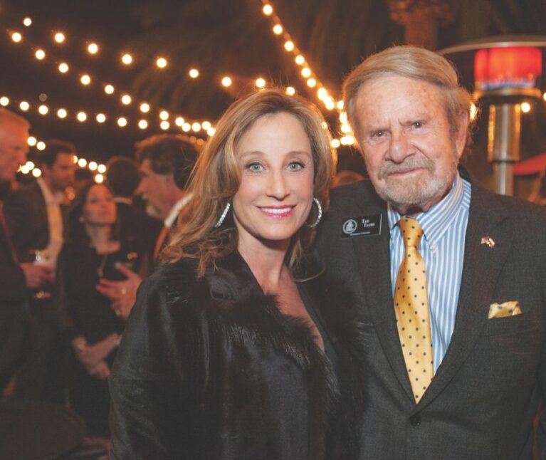 Two adults at a event posing and smiling at the camera.
