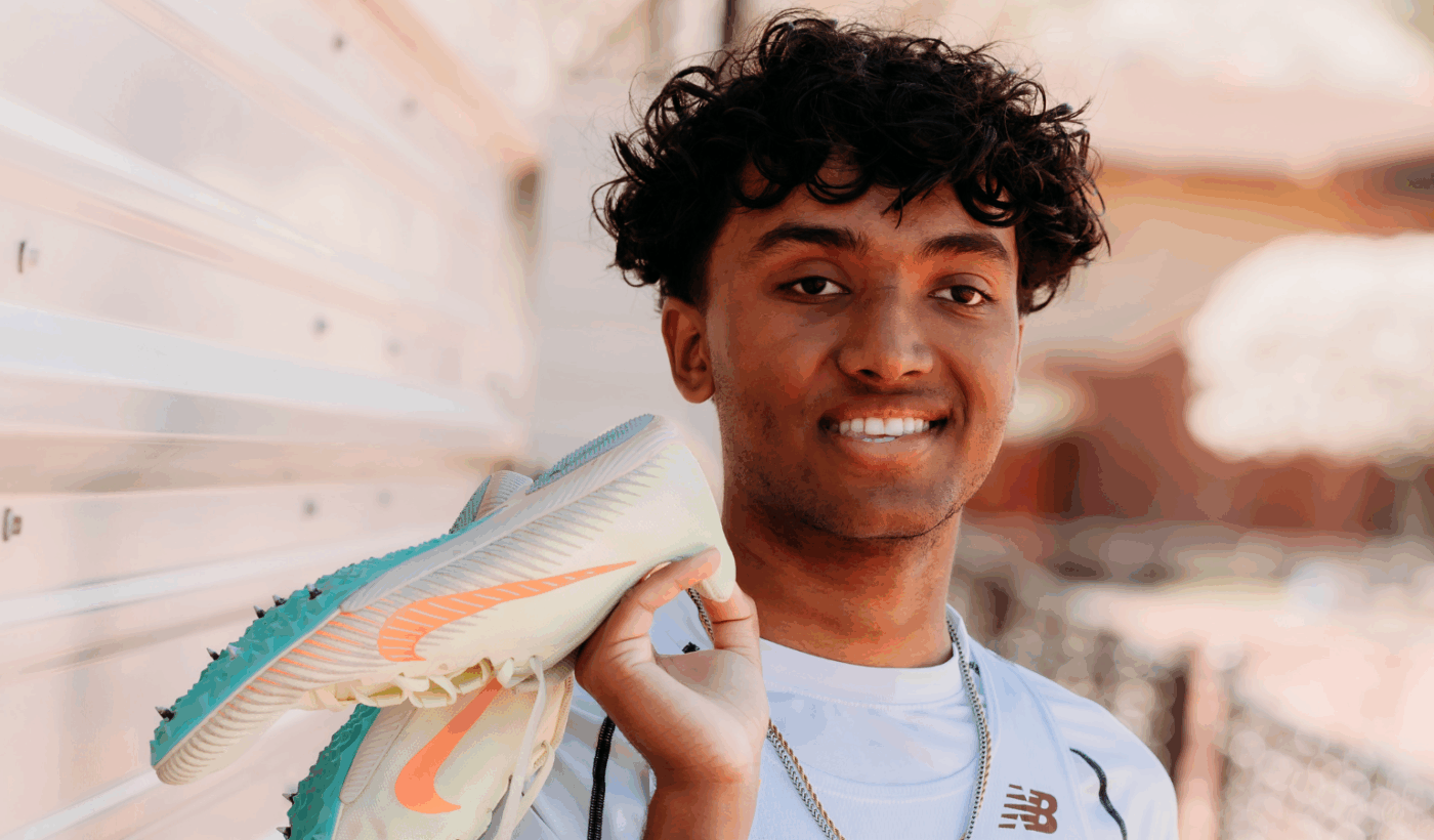 Teenage patient wearing soccer uniform and holding soccer cleats while smiling at the camera.