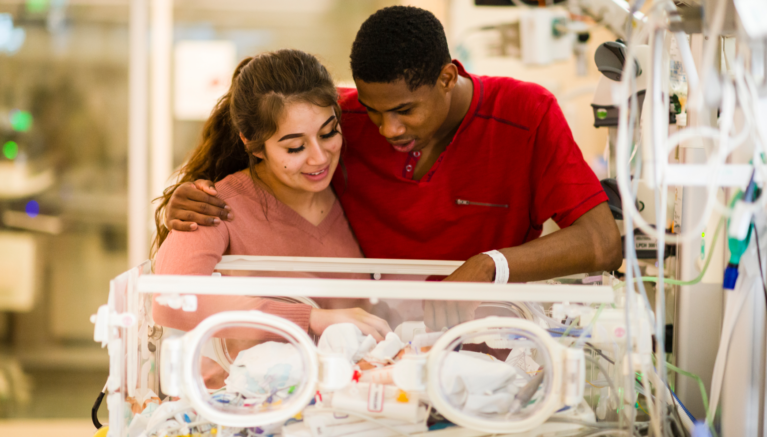 Parents looking at their newborn in the NICU