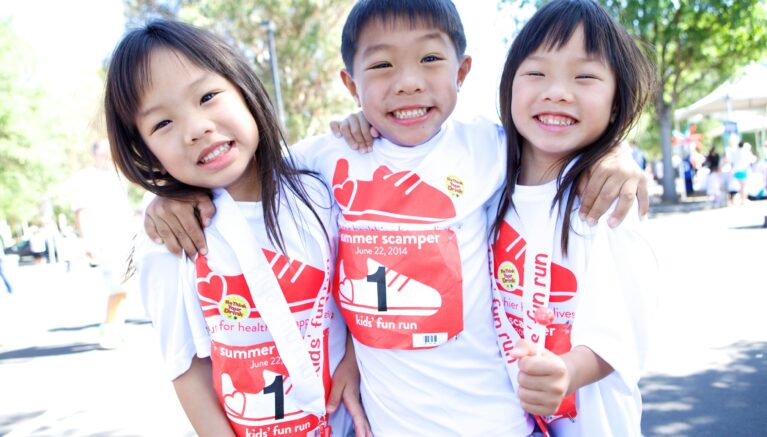 Three kids smile at Summer Scamper fundraiser event