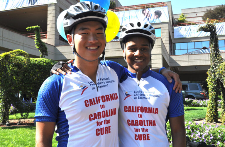 Two college students in bike riding gear raising money for childhood cancer