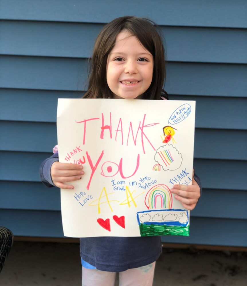 A young patient holds up a hand written thank you sign