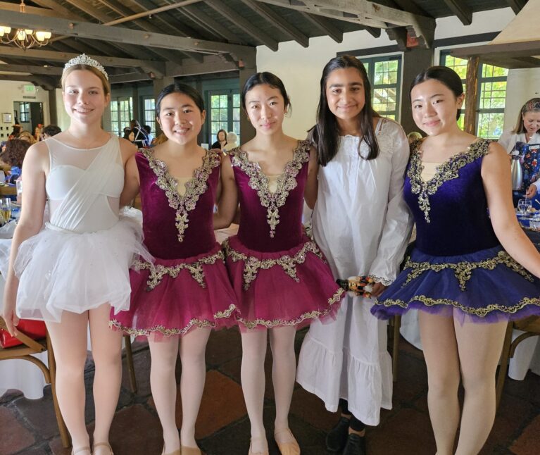 5 ballerinas pose together dressed in Nutcracker ballet costumes.