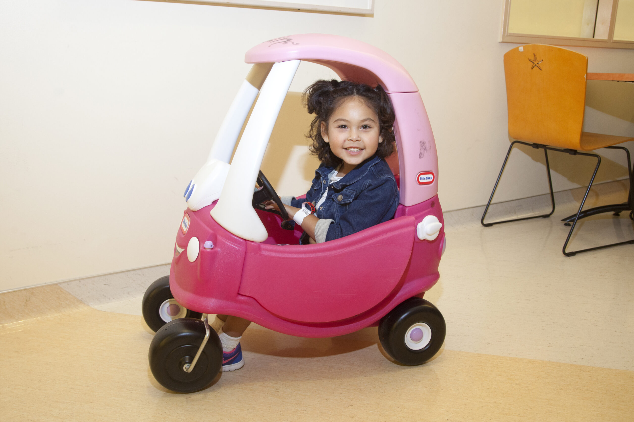 Young leukemia patient sitting in a toy car