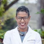 Dr. Amanda Williams smiles wearing her white lab coat.
