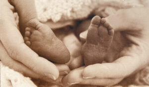 Tiny baby feet are held in his mom's hands.