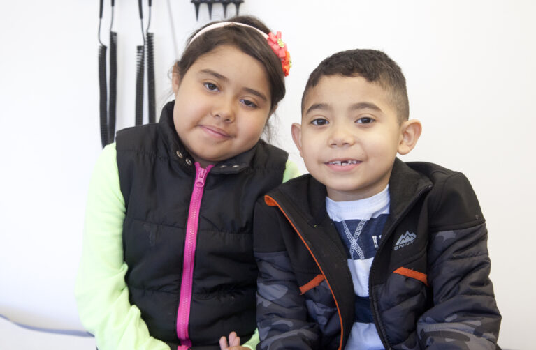 A brother and sister are seated next to one another.