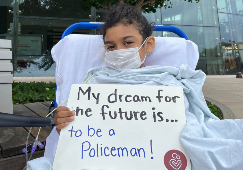 Patient holding a white board that reads "My dream for the future is to be a policeman."