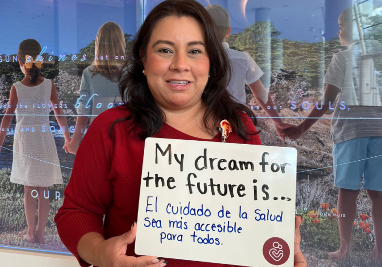 Hospital staff holding a white board that reads "My dream for the future is El cuidado de la salud sea mas accesible para todas."