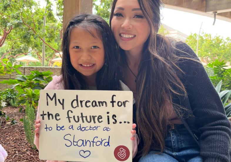 Patient holding a white board that reads "My dream for the future is to be a doctor at Stanford."