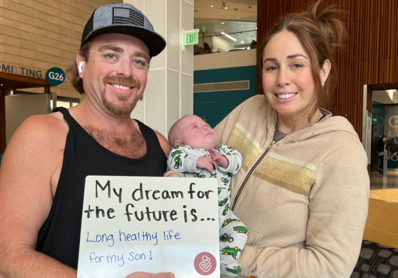 Patient family holding a white board that reads "My dream for the future is long health life for my son."