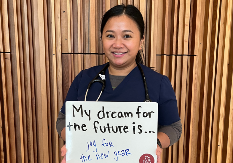 Hospital staff holding a white board that reads "My dream for the future is joy for the new year."