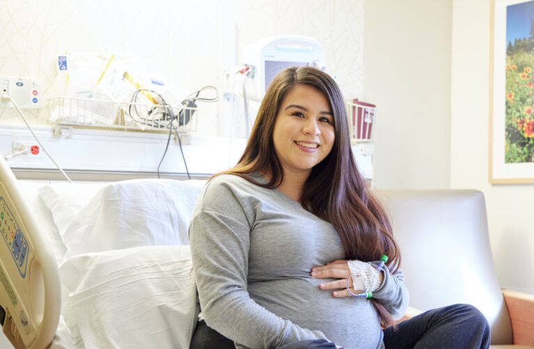 Pregnant woman seated on a hospital bed.