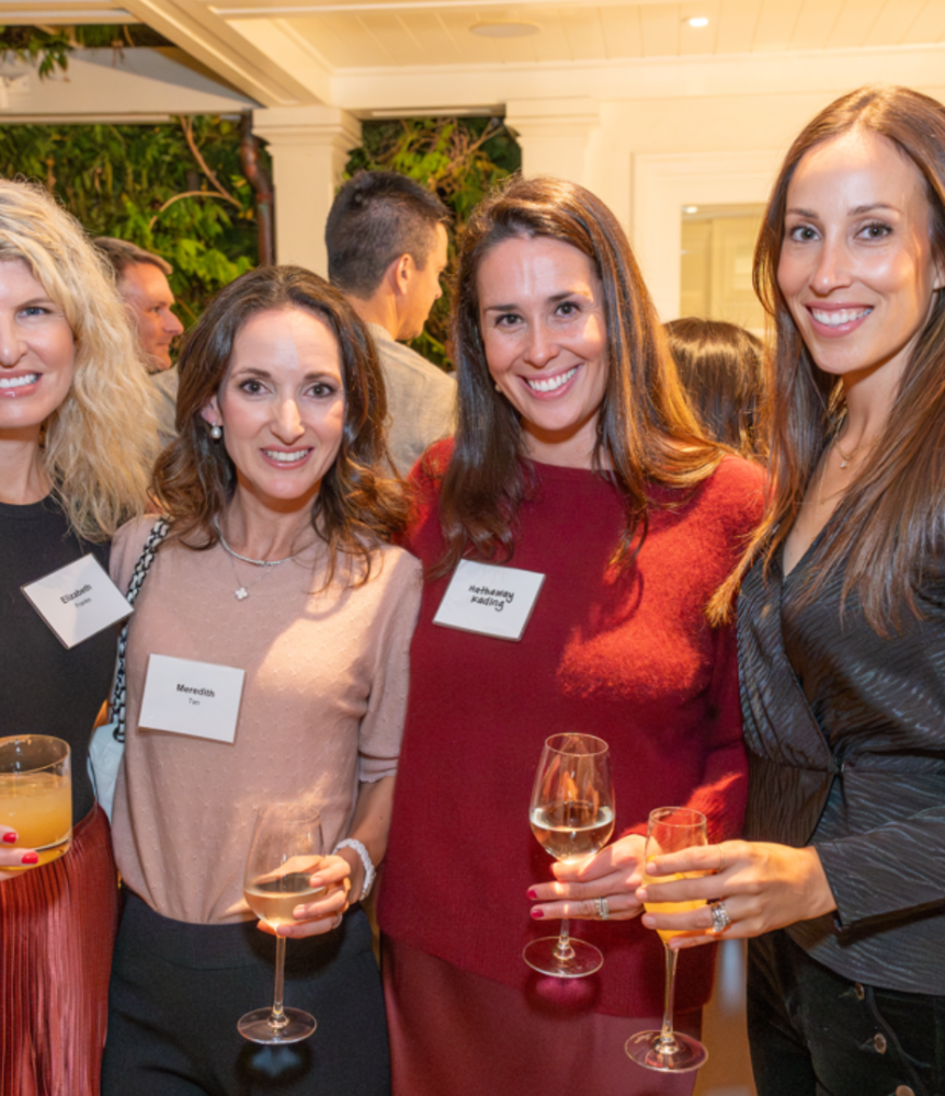 Group of four adults standing together and smiling at an event.
