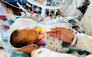 Baby swaddled in the NICU being feed with a bottle.