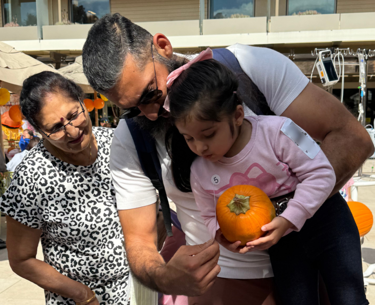A pediatric patient and two guardians selecting decorations to decorate a pumpkin at the Lucile Packard Children’s Hospital Stanford pumpkin patch.