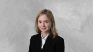 Dr. Susan Hiniker smiles at the camera while wearing a white shirt and black blazer. Dr. Hiniker sits in front of a grey backdrop.