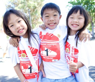 Three kids smile at Summer Scamper fundraiser event