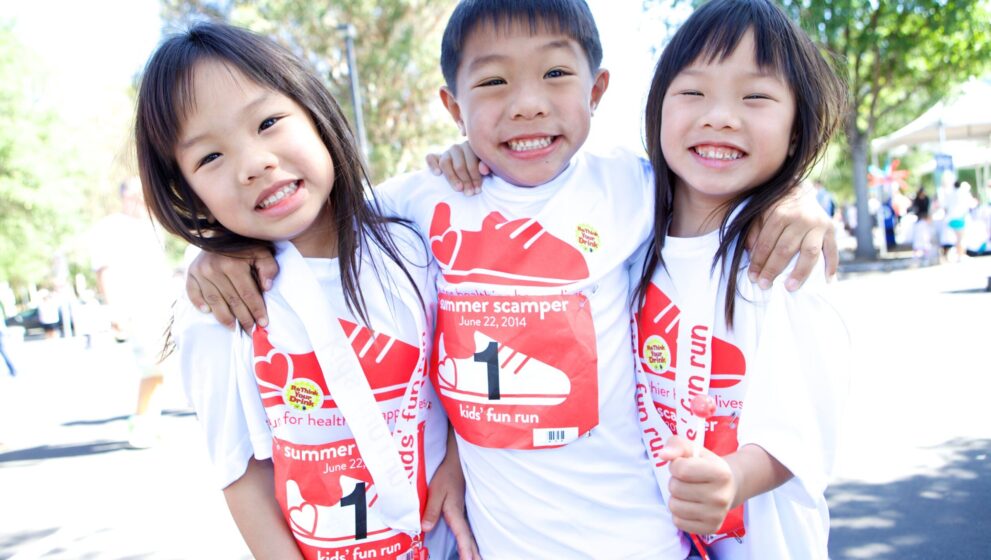 Three kids smile at Summer Scamper fundraiser event