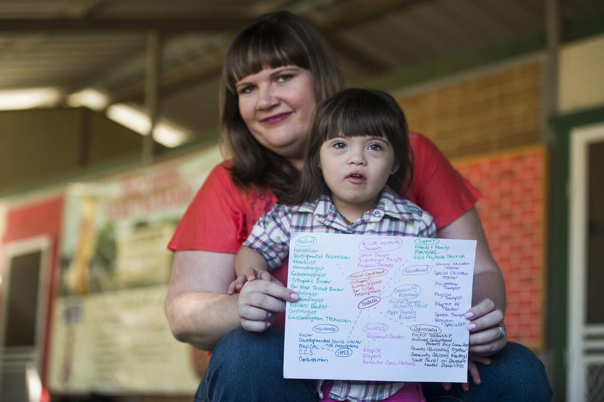 A young girl with Down syndrome and other special health care needs and her mother hold up a copy of her care map.