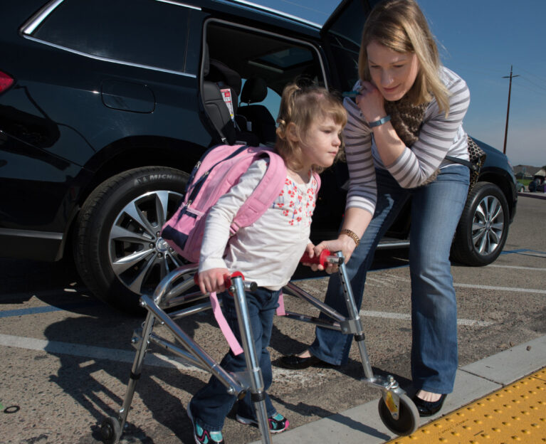 Girl with walker being helped by her mother