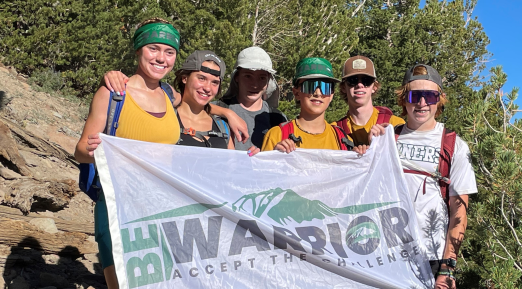 Group of hikers holding Be Warrior banner.