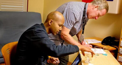 Cancer patient sitting at a table analyzing various cups.