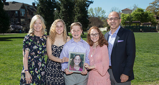 Family posing for a photo with a picture of a teen.