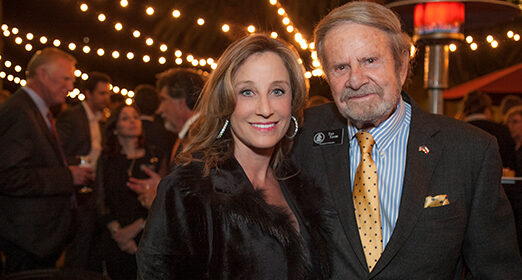 Two adults smiling at the camera at a party.