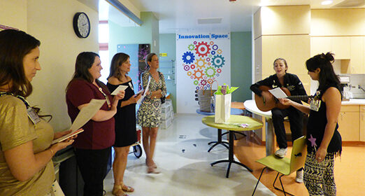 A group of adults singing with one guitarist.