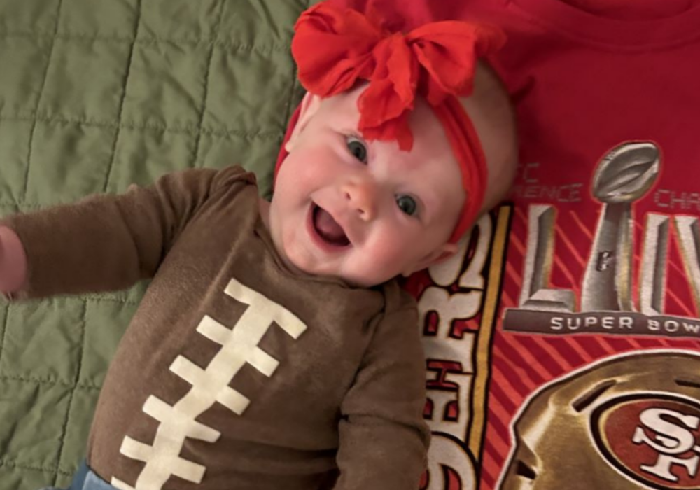 Smiling baby wearing football onesie.