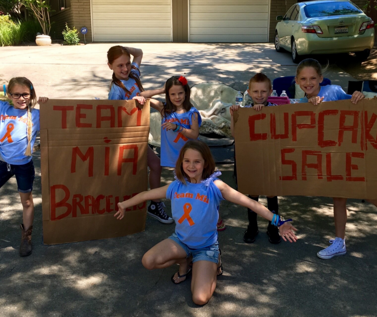 Group of children with signs encouraging friend Mia.