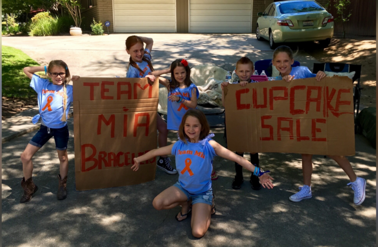 Group of children with signs encouraging friend Mia.