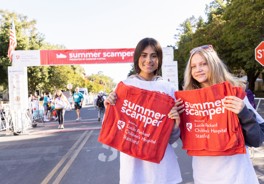 Two volunteers of Summer Scamper holding towels for participants.