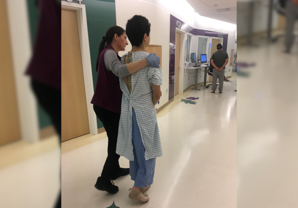 Dillon walking with nurse after his scoliosis surgery.