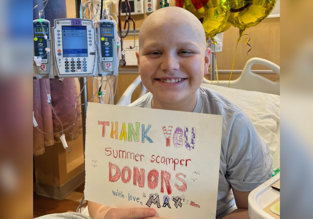 Max holding up thank you donors sign.