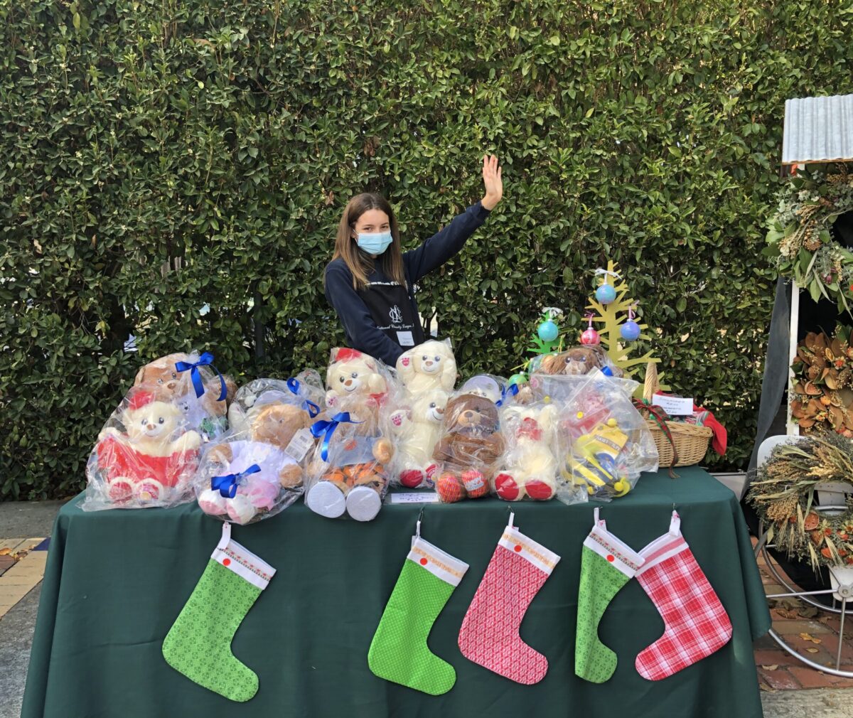 A young woman is at a table selling holiday items, including stockings.