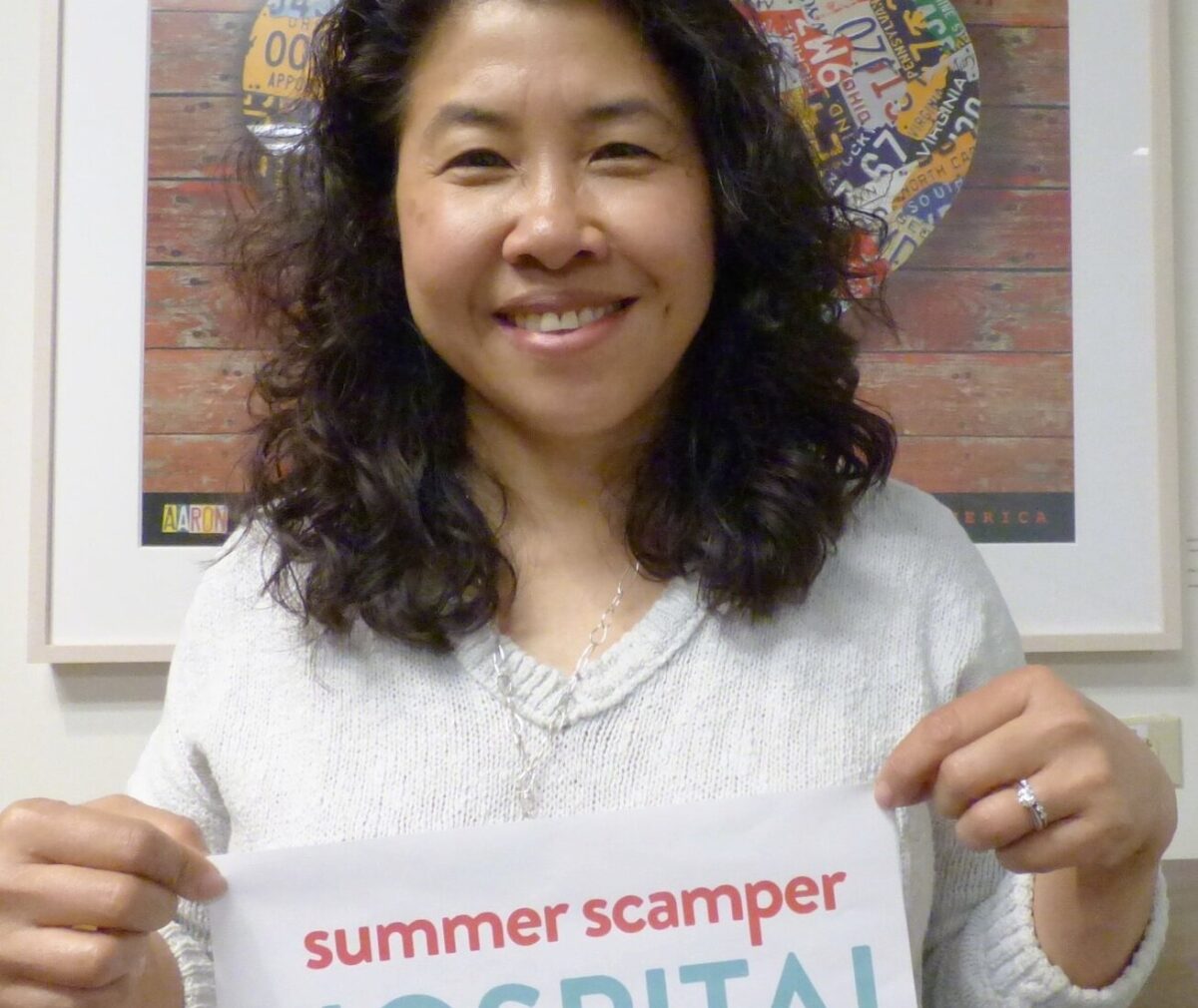 Adult holding a banner and smiling at the camera.