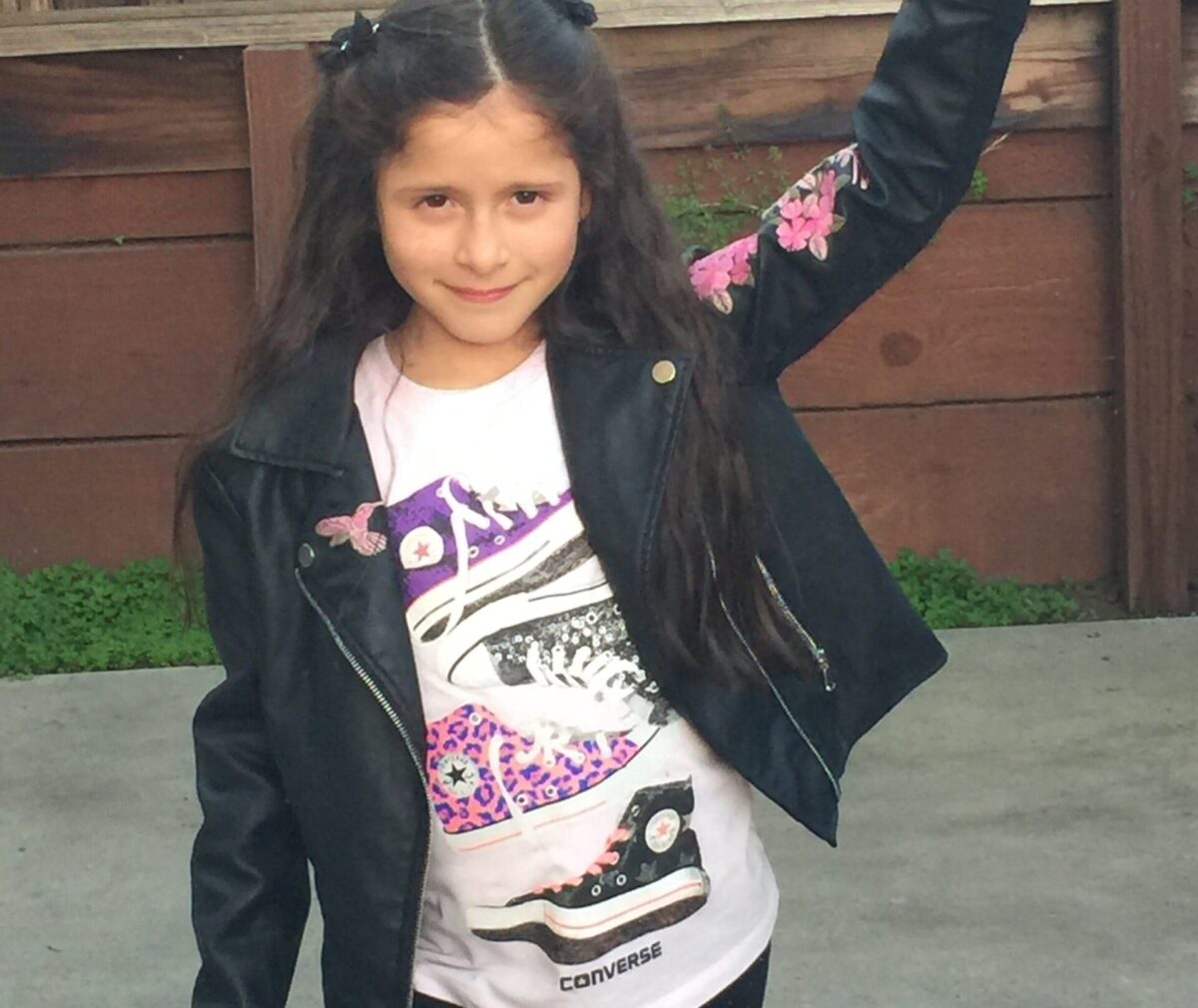 Child with hand in the air posing for a photo.