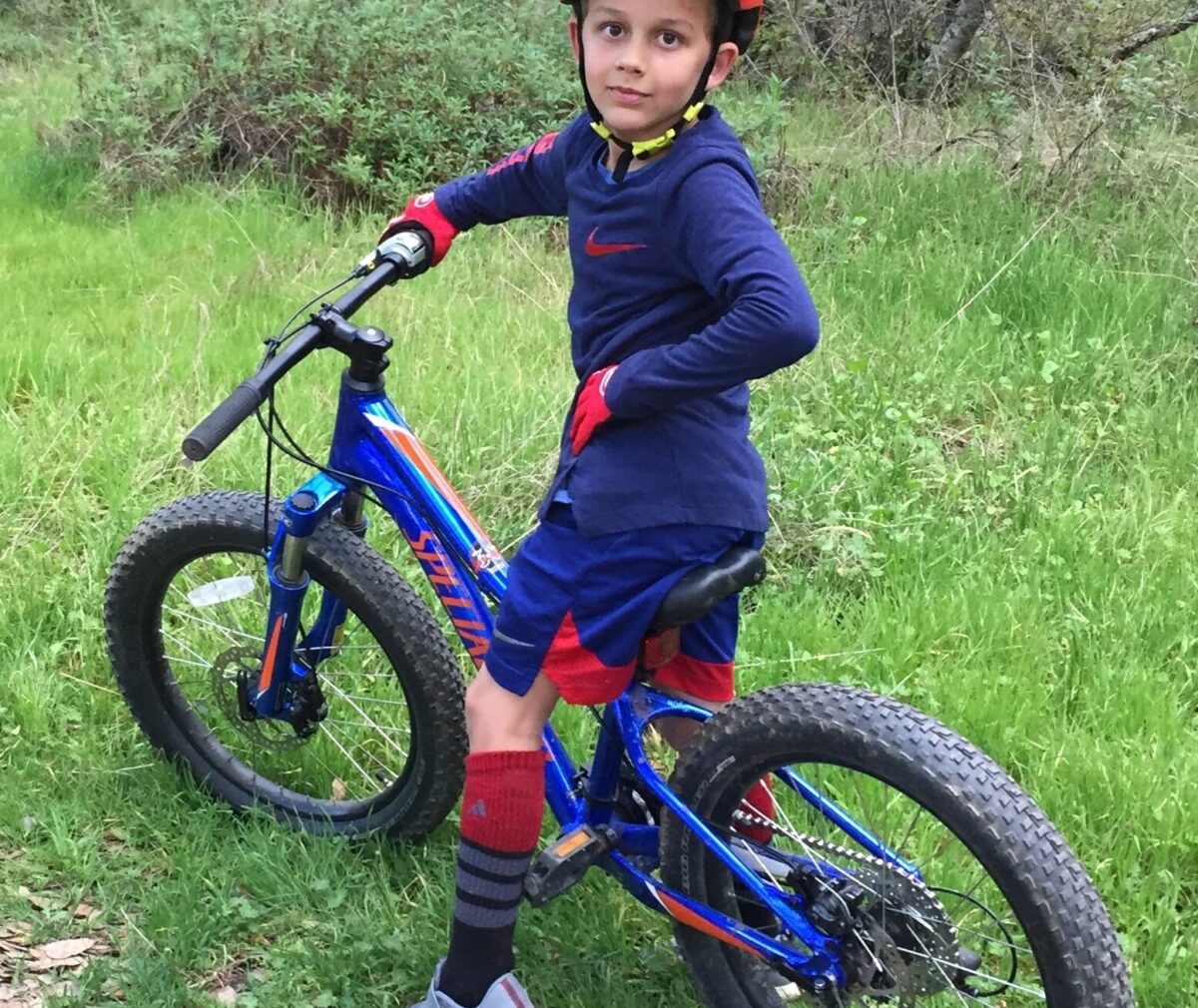 Child sitting on bike, smiling at camera.
