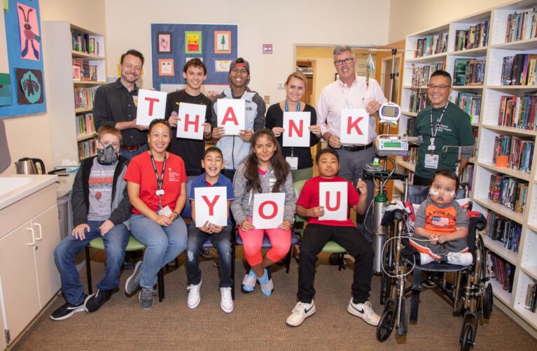 Group of doctors and children holding letters spelling out thank you.