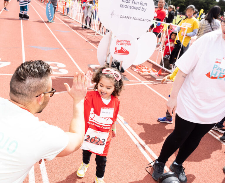 Young girl giving a high-five to a man at the end of the kids' fun run.